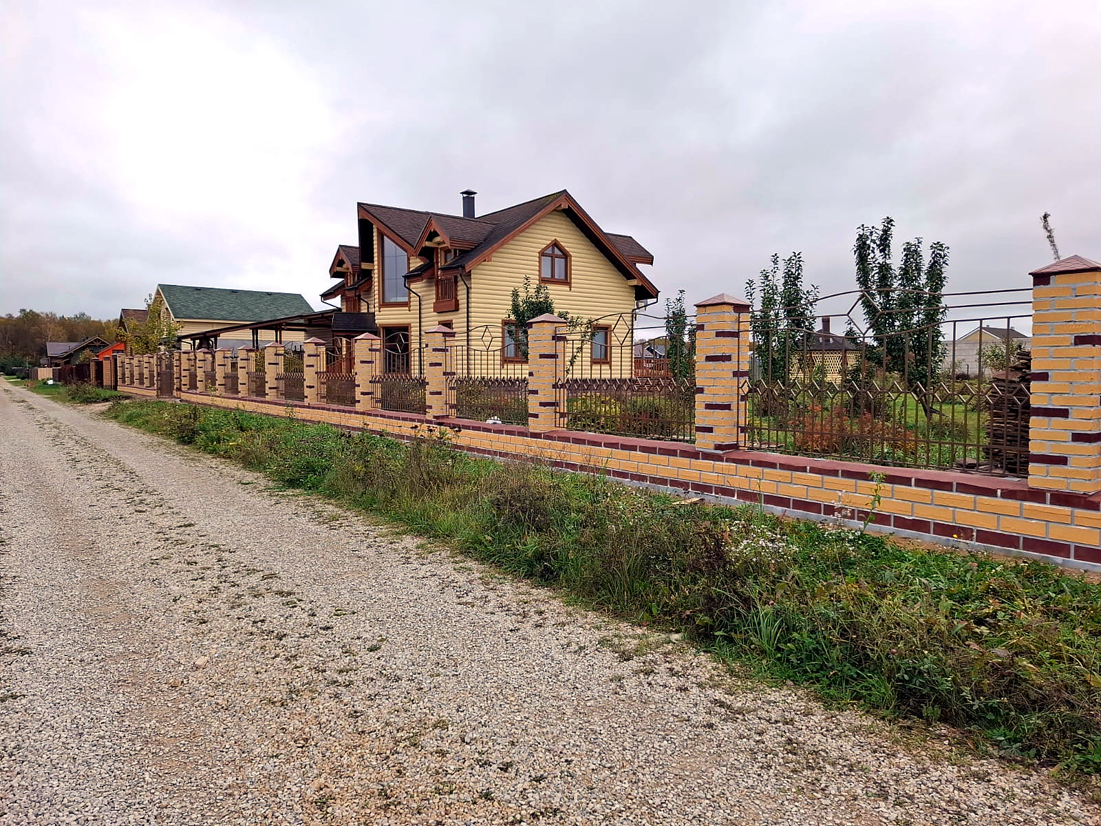 Декоративный металлический забор на кирпичном основании у загородного дома